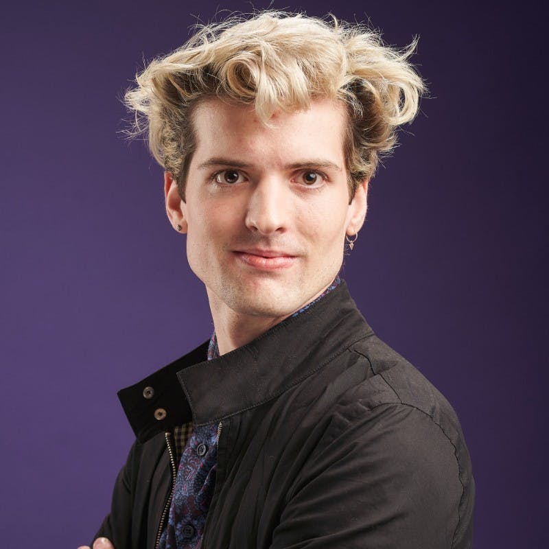 A man with blonde hair wearing a black jacket