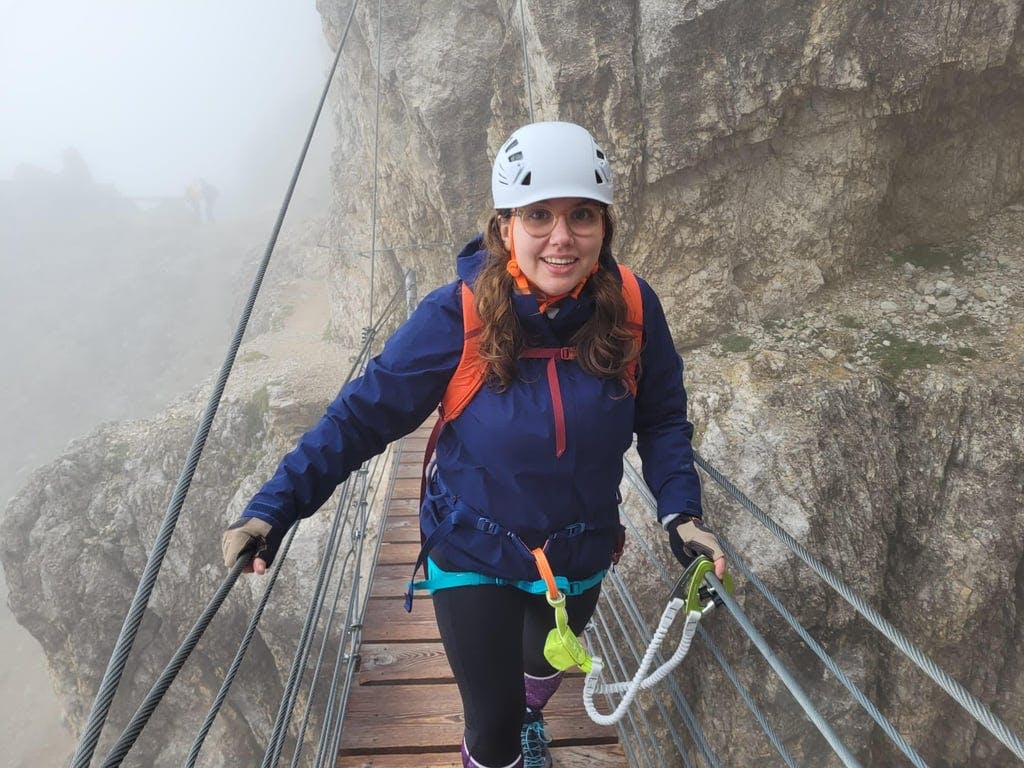A woman on a rope bridge with a helmet on