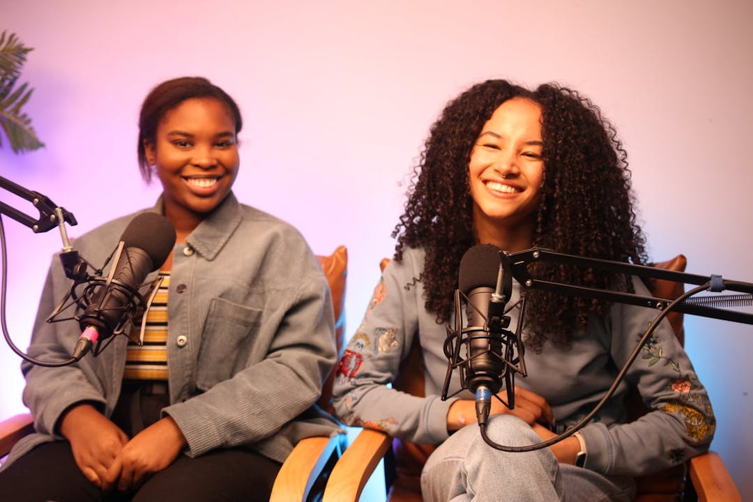 Two women sitting next to each other in front of microphones