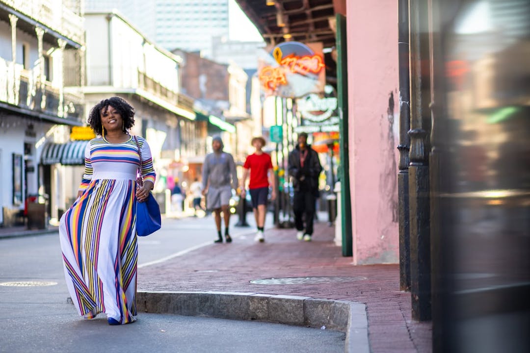 A woman is walking down the street in a colorful dress