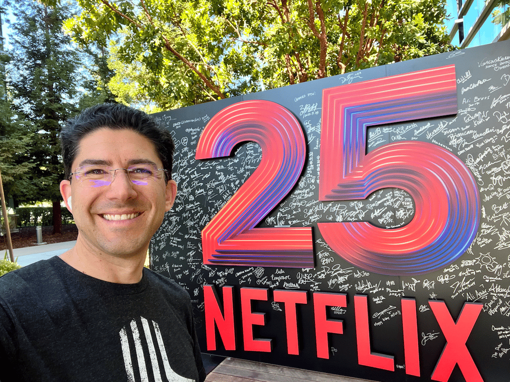 A man standing in front of a large sign that says "25 Netflix"