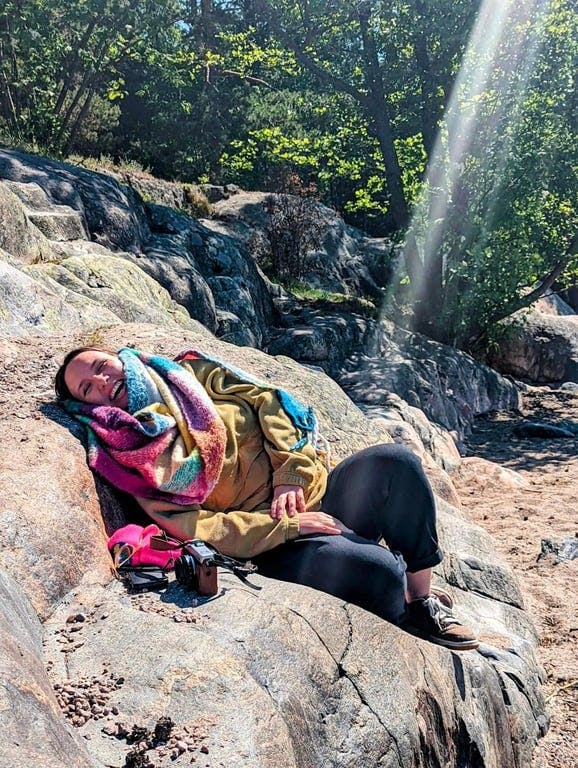 A woman laying on top of a large rock