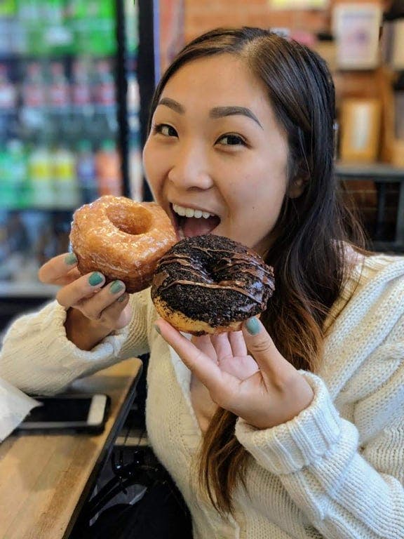 A woman holding two donuts in front of her face